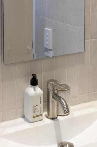 a bottle of soap sitting on a bathroom sink at The Nest - Modern Studio Retreat with Parking in Christchurch