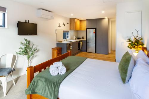 a bedroom with a large bed with two towels at The Nest - Modern Studio Retreat with Parking in Christchurch