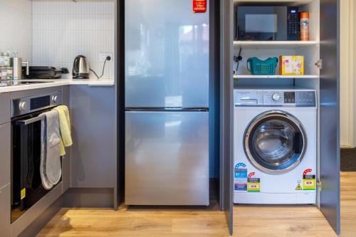 a kitchen with a refrigerator and a washer and dryer at The Nest - Modern Studio Retreat with Parking in Christchurch