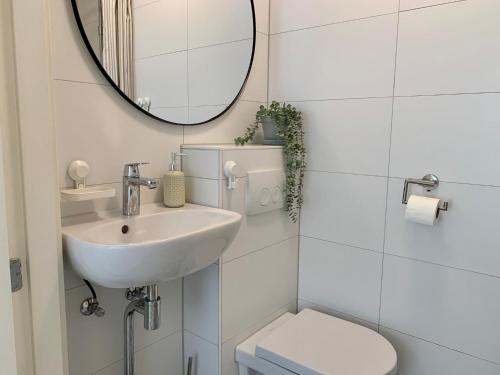 a bathroom with a sink and a toilet and a mirror at Holiday Home in Petten near the Beach in Sint Maartensvlotbrug