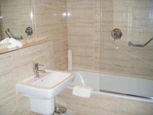uma casa de banho com um lavatório, um WC e uma banheira em Casey's Hotel em Glengarriff