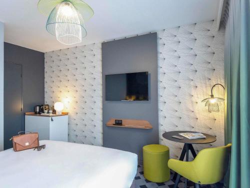 a bedroom with a bed and a table and a chair at Mercure Hyères Centre Côte d'Azur in Hyères