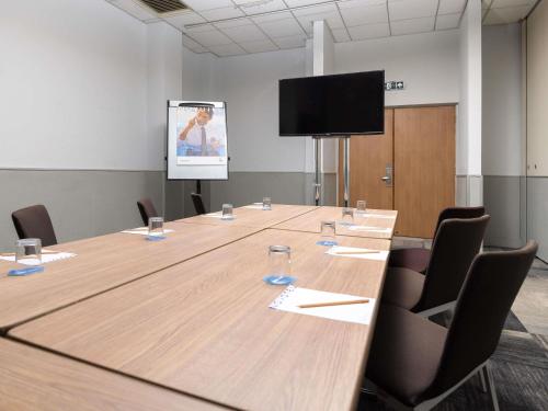 a conference room with a large table and a screen at Novotel Southampton in Southampton