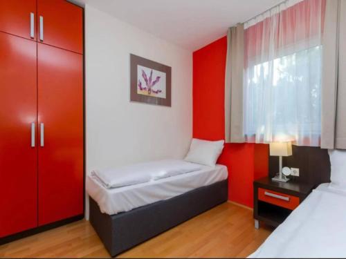 a room with two beds and a red accent wall at Marina Portoro Family Friendly Apartment 3 - Two Bedroom Apartment in Lucija