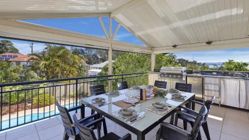 a dining room with a table and chairs on a balcony at Sunset On View - Picturesque Coastal Setting With Pool in The Entrance