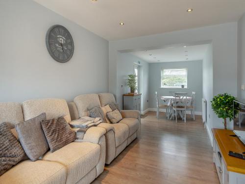 a living room with a couch and a clock on the wall at Lamsey Cottage in Heacham