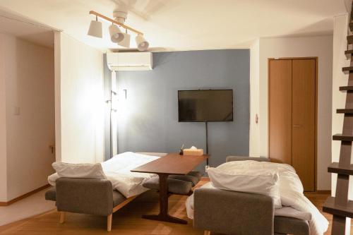 a room with a table and chairs and a tv at AsashiobashiBase in Osaka