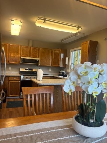a kitchen with wooden cabinets and a vase of flowers at Upscale Anchorage Getaway, Cozy & Newly Remodeled in Anchorage