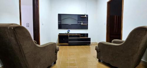 a living room with two chairs and a flat screen tv at Casa 3 quartos ar condicionado perto do centro in Montes Claros