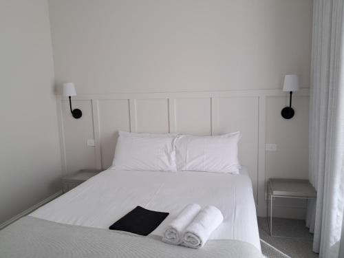 a white bed with two rolled towels on it at Dormie House in Moss Vale