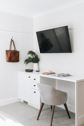 a white desk with a tv and a chair at Dormie House in Moss Vale