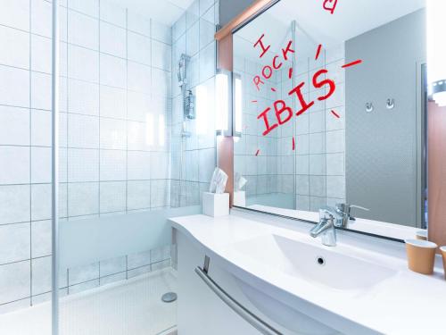 a white bathroom with a sink and a mirror at Hôtel Ibis Cognac Centre in Cognac