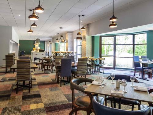 a restaurant with tables and chairs and windows at Novotel Newcastle Airport in Newcastle upon Tyne