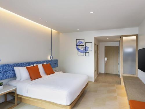 a bedroom with a white bed and orange pillows at Novotel Rayong Rim Pae Resort in Klaeng