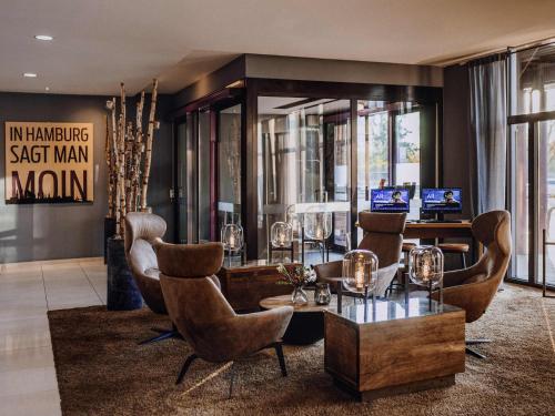 a lobby with chairs and a table with wine glasses at Mercure Hotel Hamburg City in Hamburg