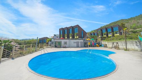 a large blue swimming pool in front of a building at Geojedo Pilos Ocean View Pension in Geoje 