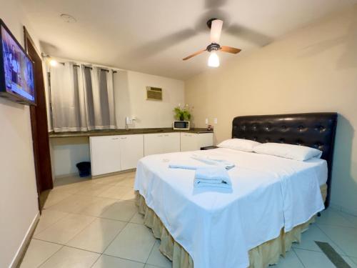a bedroom with a large white bed with a ceiling fan at VA Apart Hotel Savassi in Divinópolis