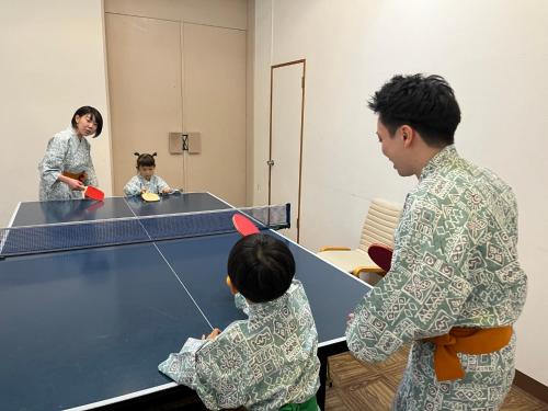 a group of people standing around a ping pong table at Kusatsu Onsen Hotel Village in Kusatsu