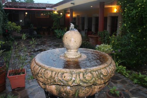 a large stone fountain in a garden in front of a house at Hotel Art Gallery Casona de los Milagros in Colima
