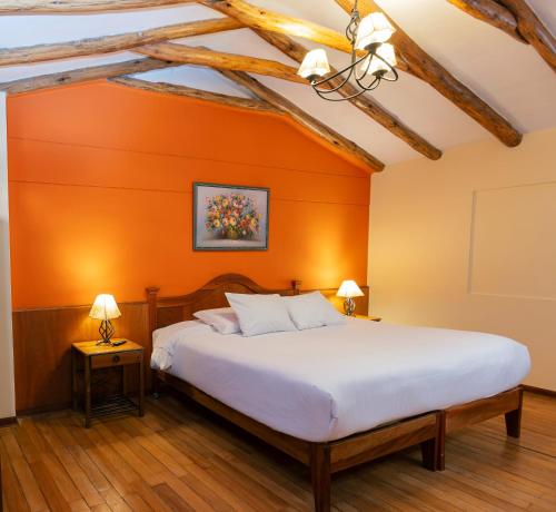 a bed in a room with an orange wall at Amerindia in Cusco