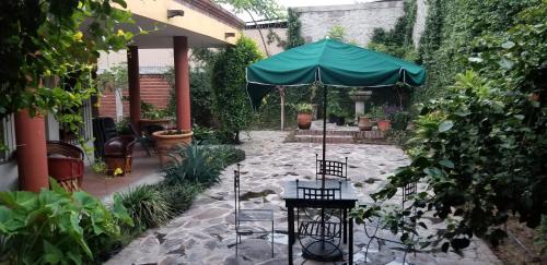 a patio with an umbrella in a garden at Hotel Art Gallery Casona de los Milagros in Colima