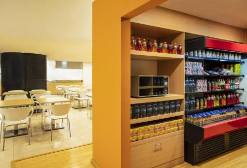 a restaurant with a cafeteria with tables and drinks at Fiesta Inn Express Queretaro Constituyentes in Querétaro