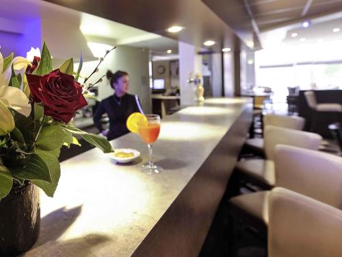 a woman sitting at a bar with a drink at Mercure Rouen Val de Reuil in Val de Reuil