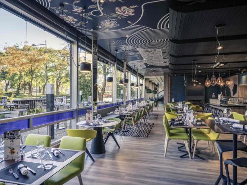 a restaurant with tables and chairs and windows at Mercure Mulhouse Centre in Mulhouse