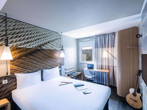 a hotel room with a large white bed and a guitar at Hotel ibis Porto Gaia in Vila Nova de Gaia
