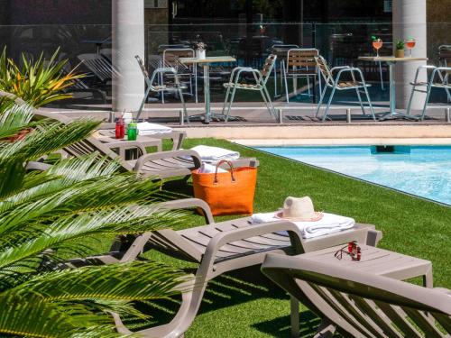 a group of chairs and tables next to a pool at ibis Hyeres Centre in Hyères
