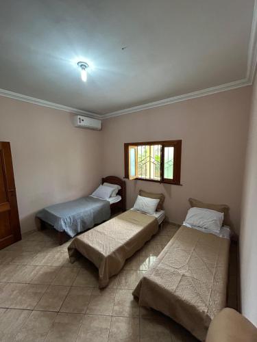 a room with three beds and a window at COP30 house in Ananindeua