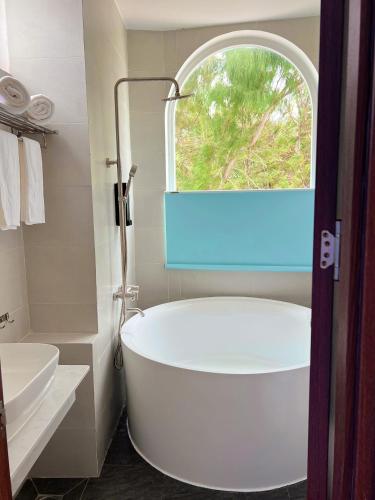 a white bath tub in a bathroom with a window at Babylon Hotel Phu Quy in Îlot du Sud