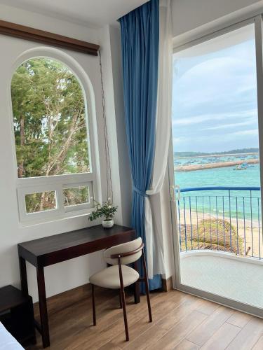 a bedroom with a desk and a view of the ocean at Babylon Hotel Phu Quy in Îlot du Sud
