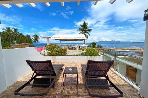 two chairs and a table on a balcony with the ocean at Arkipelago Divers and Beach Resort in Puerto Galera
