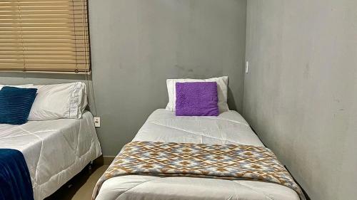 a small room with two beds and a purple pillow at 3 Quartos Com Vista Espetacular in Brasilia