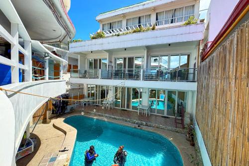 two people standing in front of a building with a swimming pool at Arkipelago Divers and Beach Resort in Puerto Galera