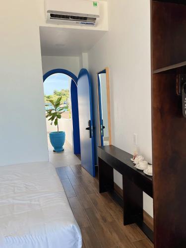 a bedroom with a bed and a desk with blue doors at Babylon Hotel Phu Quy in Îlot du Sud