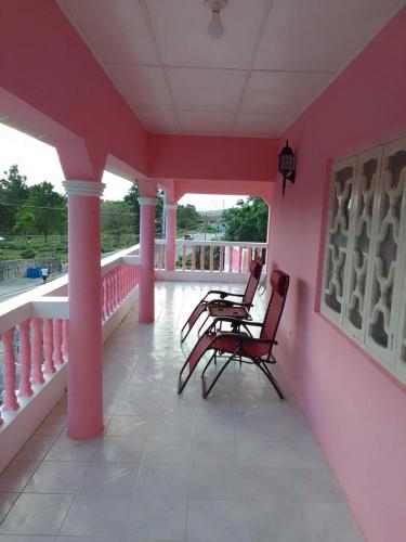 a pink room with chairs on a porch at Pink flamingo in Port Antonio