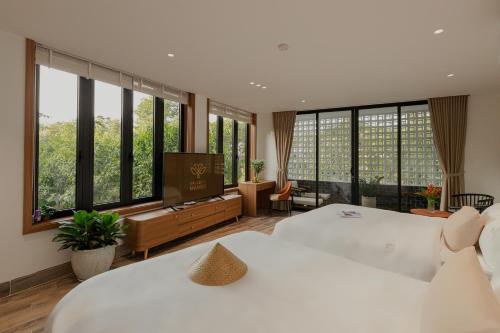 a bedroom with two beds and a television and large windows at Valley De Mango Hue in Thôn Châu Chữ