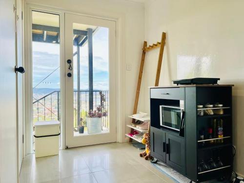 a living room with a microwave and a balcony at Hobart Retreat with City and Water View in West Hobart