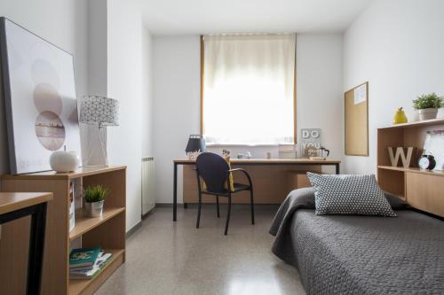 a bedroom with a bed and a desk with a chair at Residencia Universitaria Campus de Montilivi in Girona