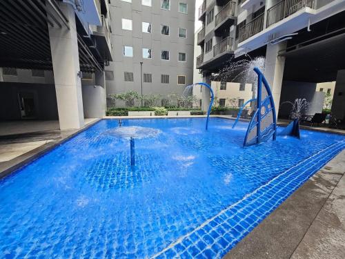 une grande piscine bleue avec un toboggan aquatique dans un bâtiment dans l'établissement S Residences Tower 1 - near MOA & Ayala Malls Manila Bay, à Manille