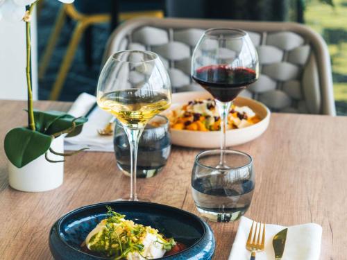 a table with two glasses of wine and a plate of food at Mercure Paris Orly Rungis Aéroport in Rungis