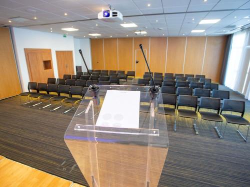 a conference room with a glass table and chairs at Novotel Bourges in Bourges