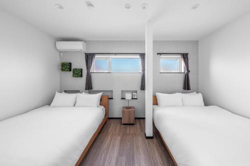 two beds in a room with two windows at Hoshiyado Nagayama in Asahikawa