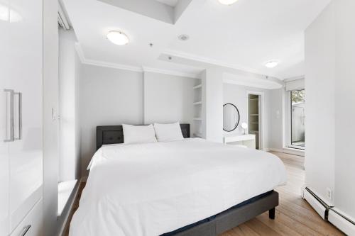a white bedroom with a large bed and a window at The Vancouver Penthouse, 2-Level, Patios, Hot Tub in Vancouver