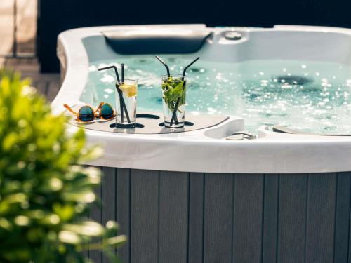 a bath tub with two glasses sitting on top of it at Mercure Nice Centre Notre Dame in Nice