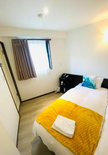 a bedroom with a large bed with a yellow blanket at Omori Happy Smile Hotel in Wada