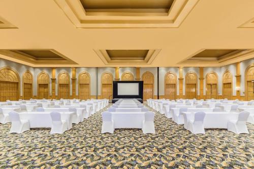 a large room with white tables and a screen at Grand Fiesta Americana Los Cabos All Inclusive Golf & Spa in Cabo San Lucas