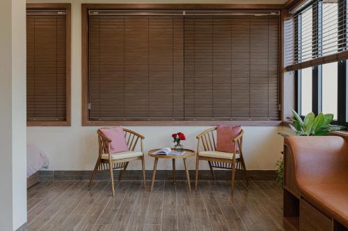 two chairs and a table in a room with windows at Valley De Mango Hue in Thôn Châu Chữ
